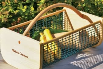 a basket with vegtables with a garden in the background