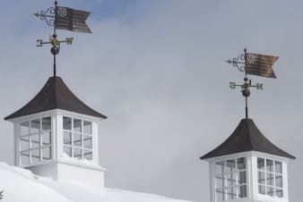 a building roof with two weathervanes